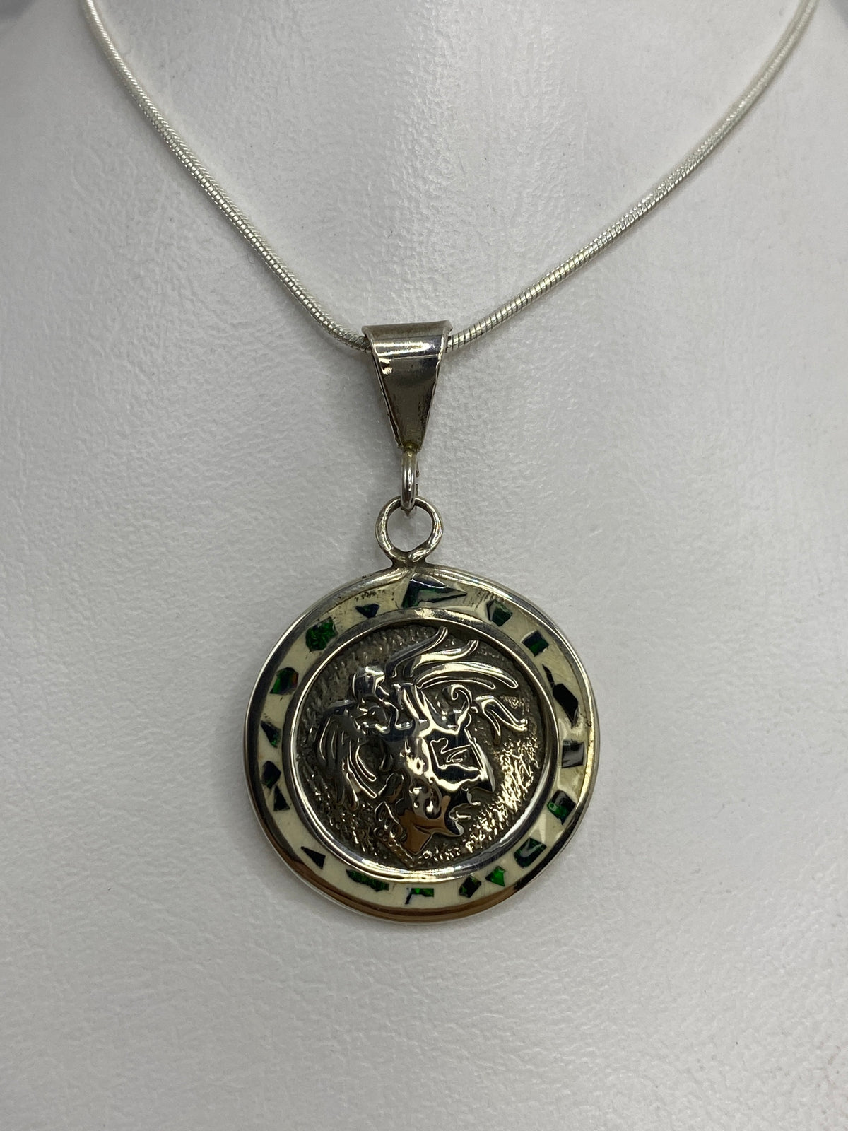 Dije de plata ópalo de fuego con diseño prehispánico, colgado de una cadena plateada