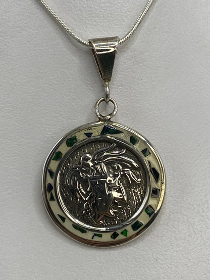 Dije de plata 3.7 cm junto a regla para escala de medida