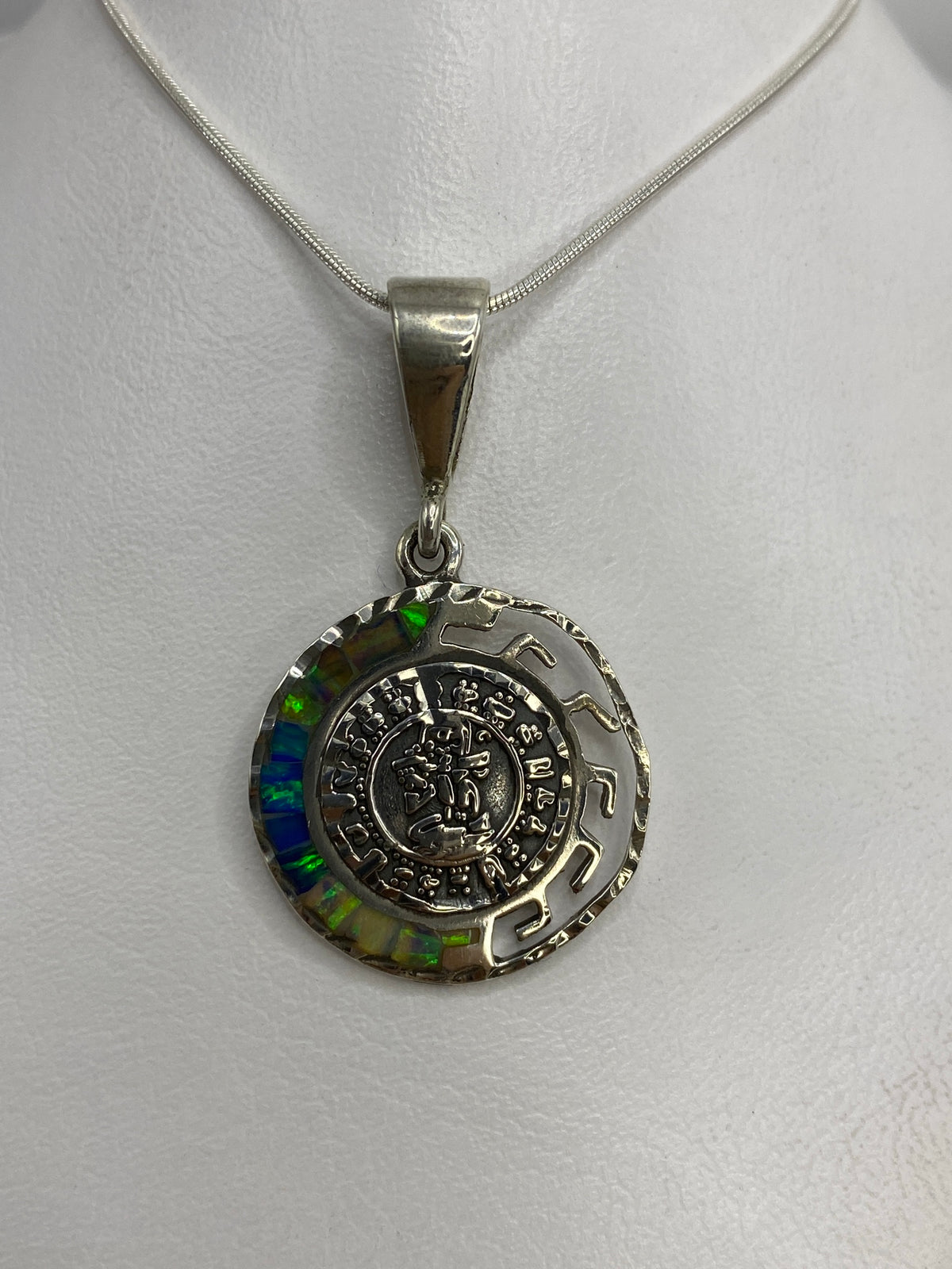Dije de plata 950 con calendario azteca y ópalo de fuego multicolor colgado de cadena de serpentina