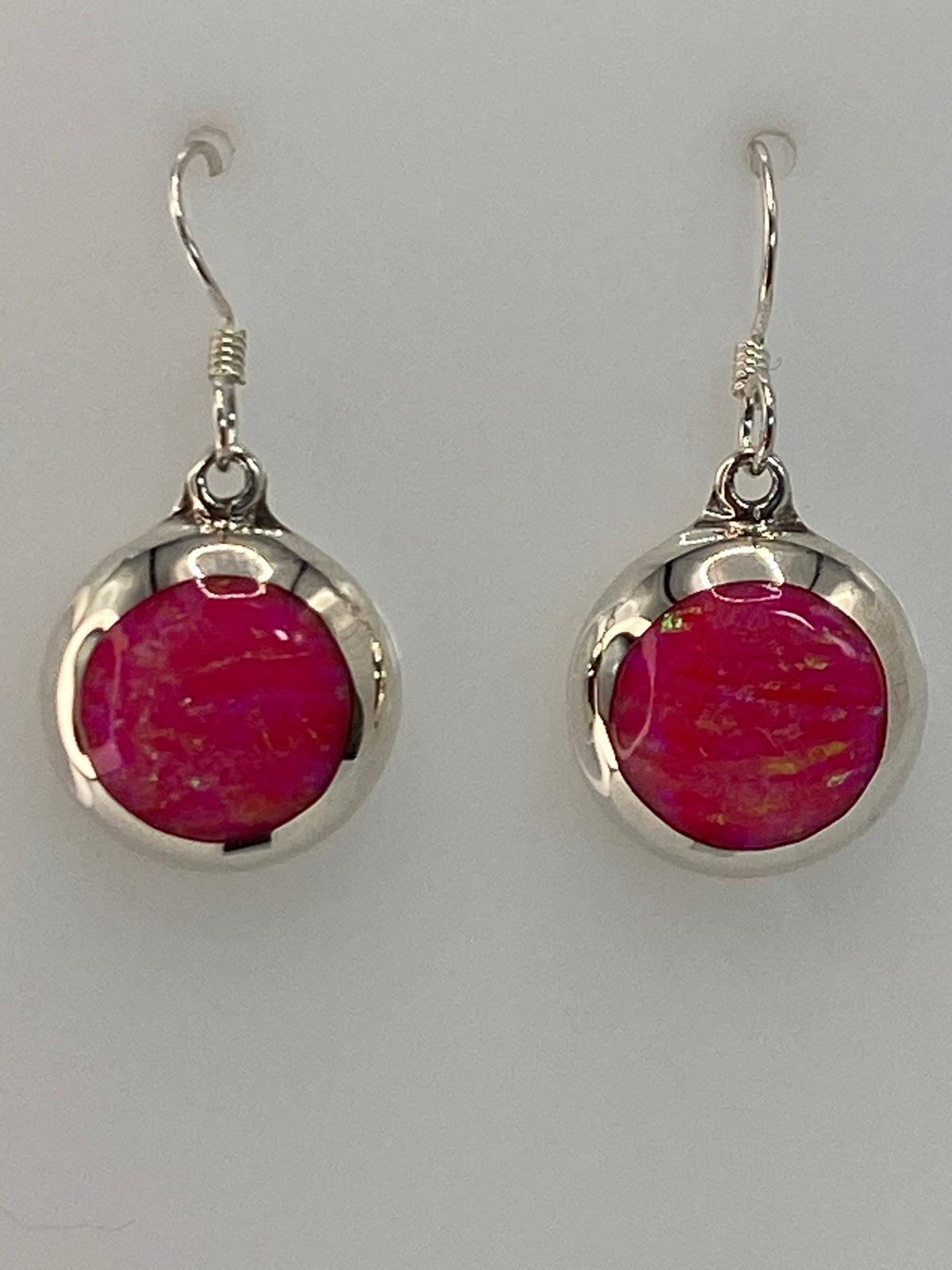 Aretes de plata con opalo de fuego rosa colgando, vista frontal