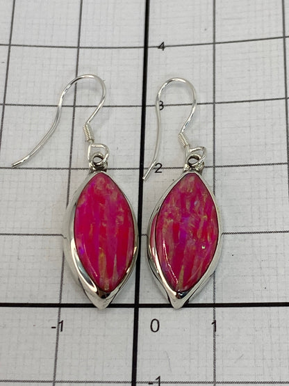 Aretes de opalo de fuego rosa brillando contra fondo blanco, 3.3 cm de largo