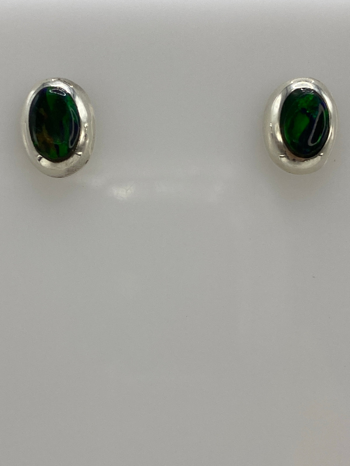 Aretes de plata con ópalo de fuego verde brillante, postes y mariposa visible