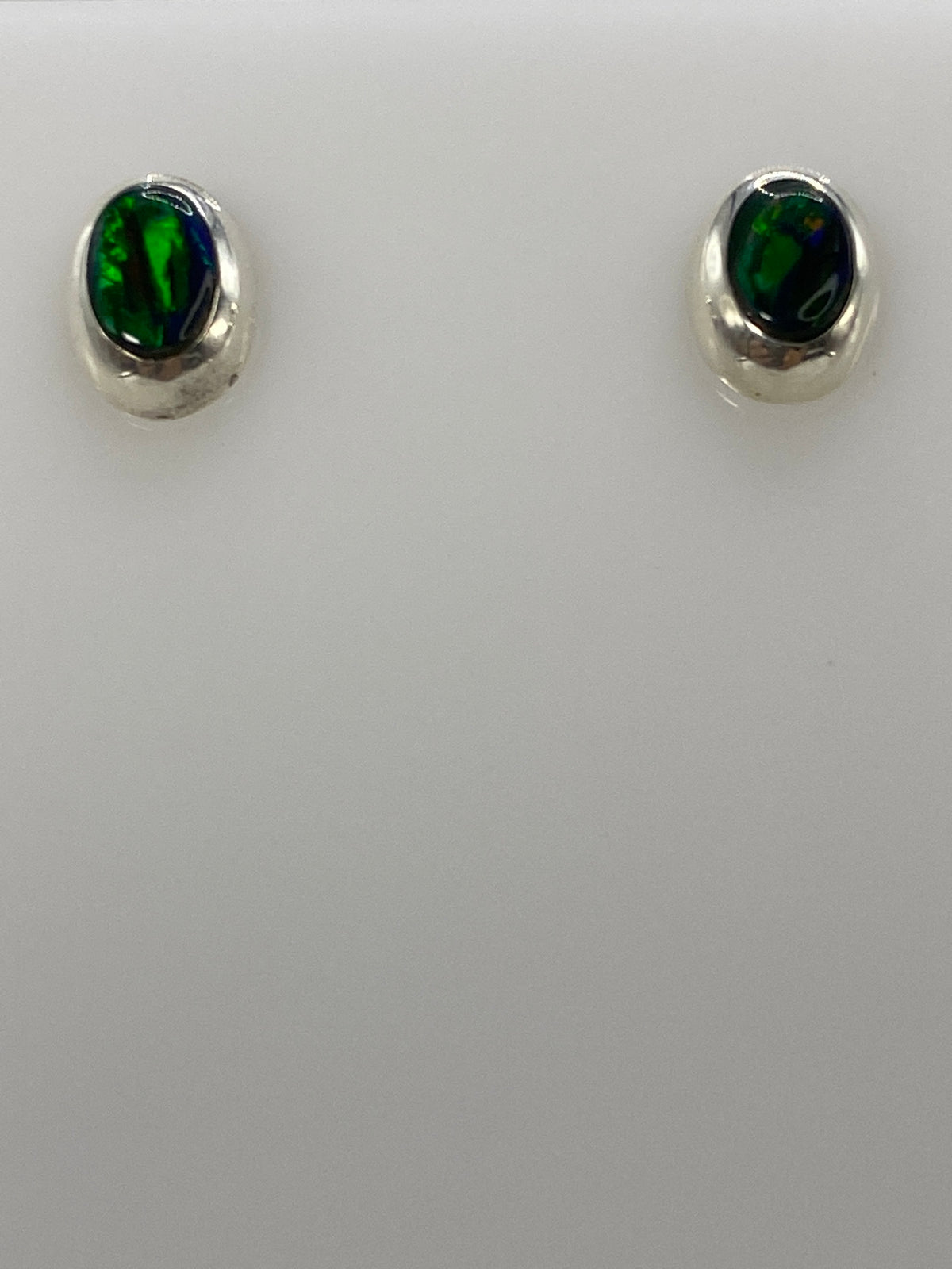 Detalle frontal de los dos aretes mostrando el color verde del ópalo y el engaste de plata