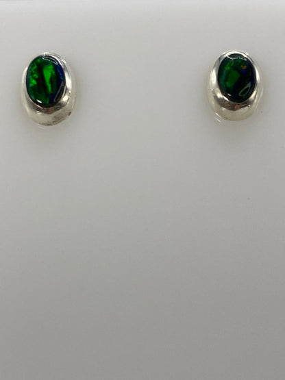 Detalle frontal de los dos aretes mostrando el color verde del ópalo y el engaste de plata