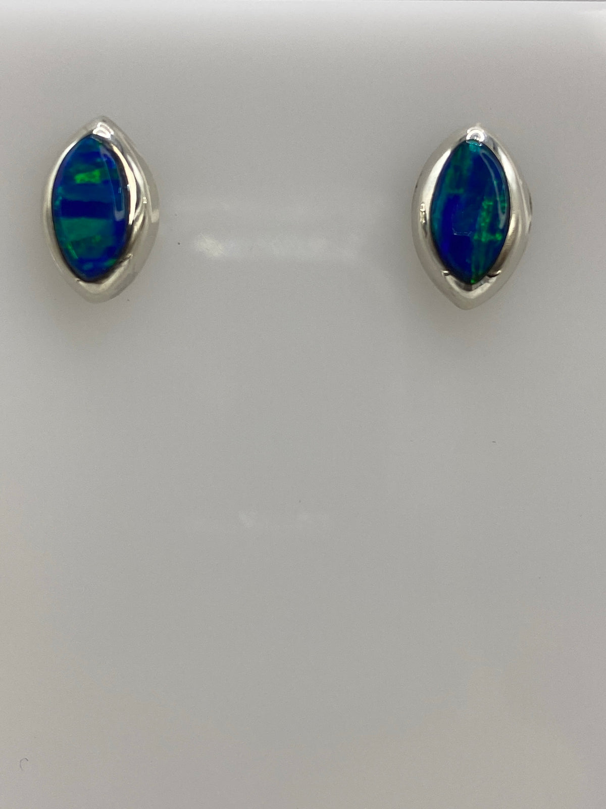 Aretes de plata con ópalo de fuego azul engastado, vistos de frente