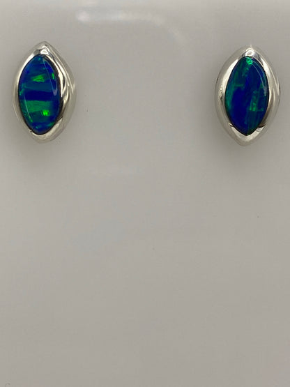 Aretes de ópalo de fuego sobre paño gris, mostrando el color azul intenso