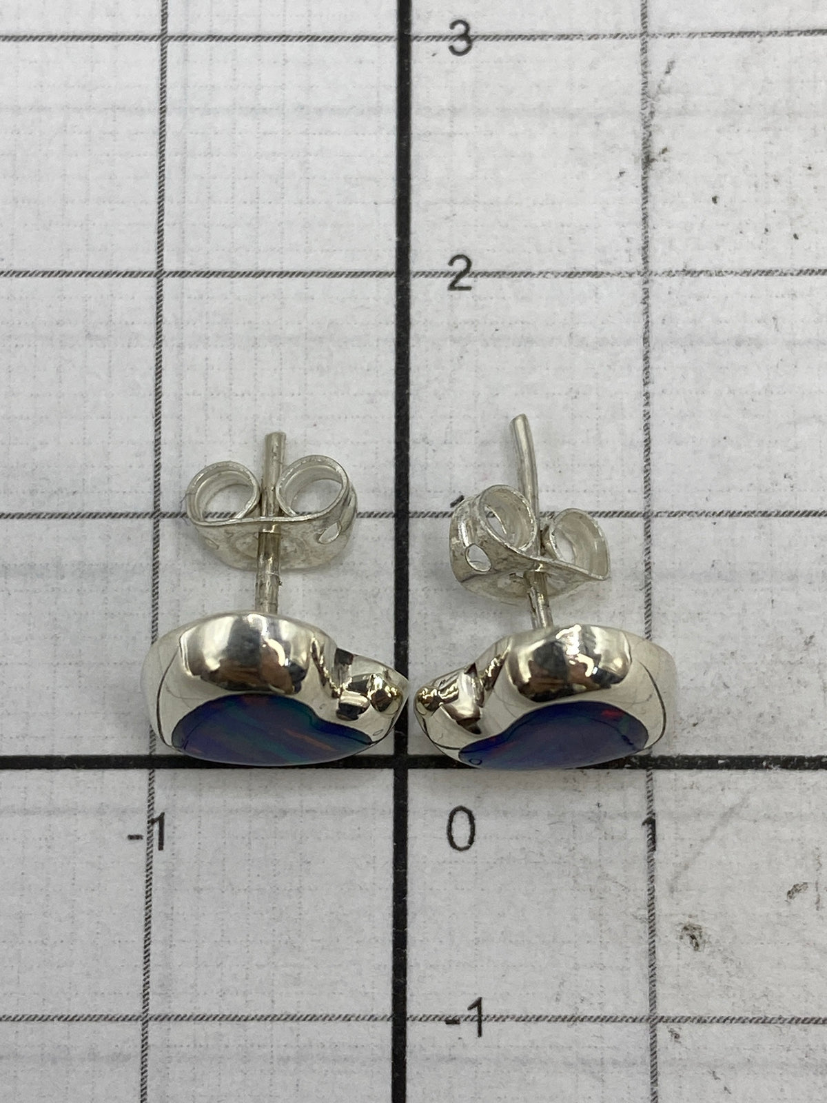 Aretes de plata con ópalo morado sobre fondo neutro
