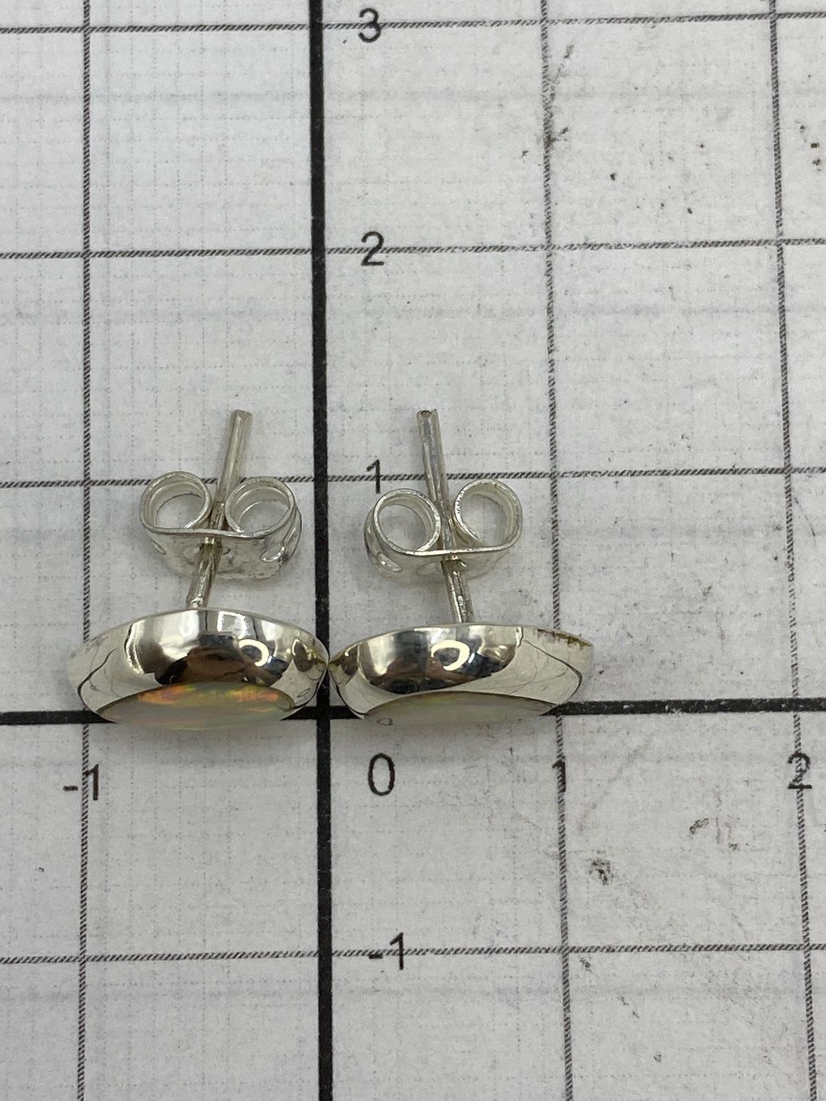 Aretes de plata Taxco con ópalo blanco sobre fondo neutro mostrando el Quinto