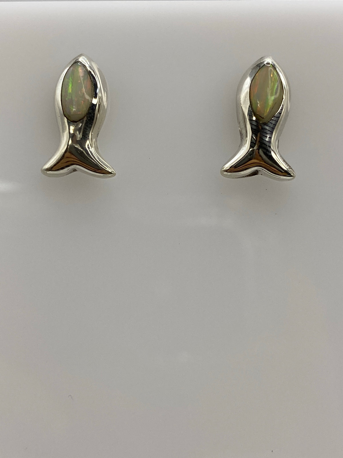 Par de aretes de plata con ópalo de fuego blanco engastado, sobre fondo blanco