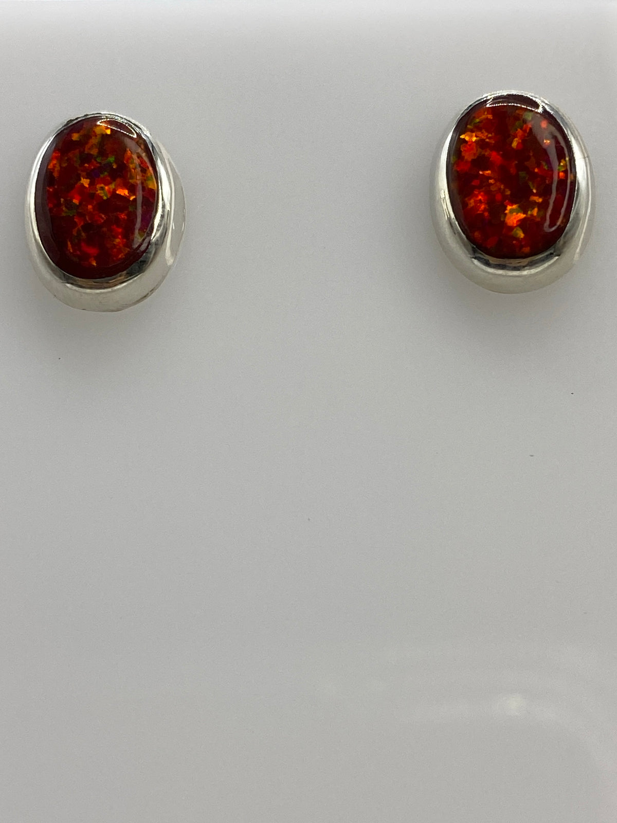 Detalle del opalo de fuego rojo en los aretes de plata, mostrando reflejo de luz