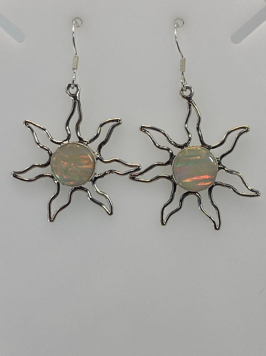 Detalle frontal de un arete sol mostrando el ópalo de fuego engastado en el centro y los rayos curvos de plata