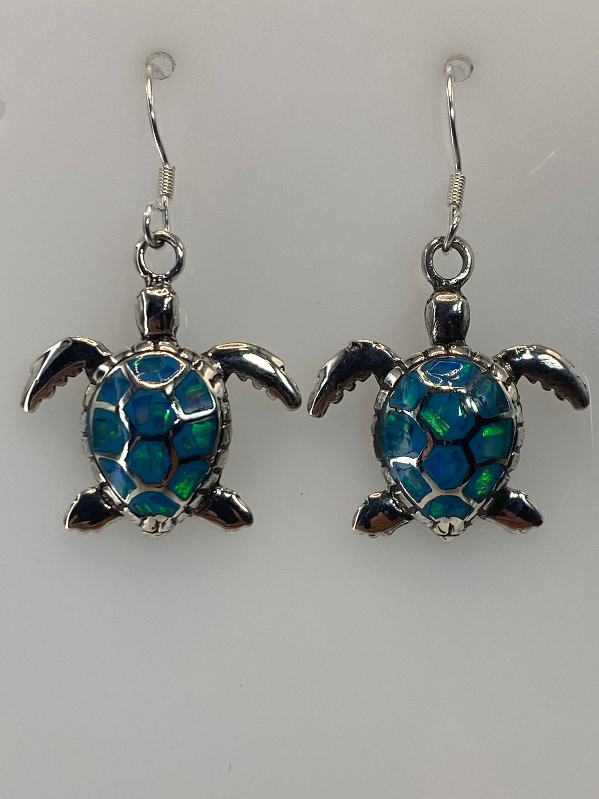 Par de aretes de plata con ópalo de fuego azul cielo, gancho de plata, sobre fondo blanco