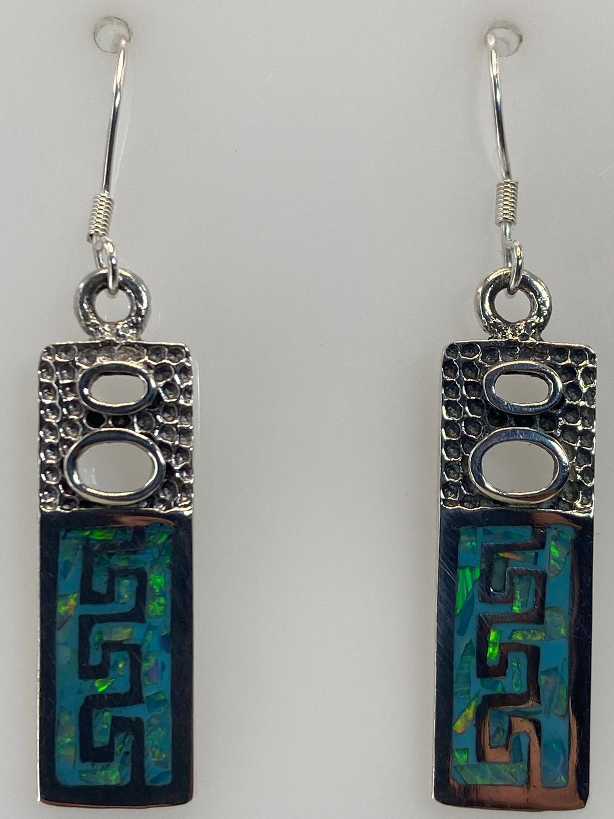 Aretes prehispánicos de Taxco colgando, mostrando la proporción de 4.1 cm y el brillo del ópalo