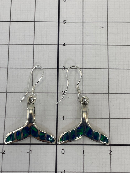 Aretes sobre fondo gris mostrando el brillo del ópalo y el pulido de la plata