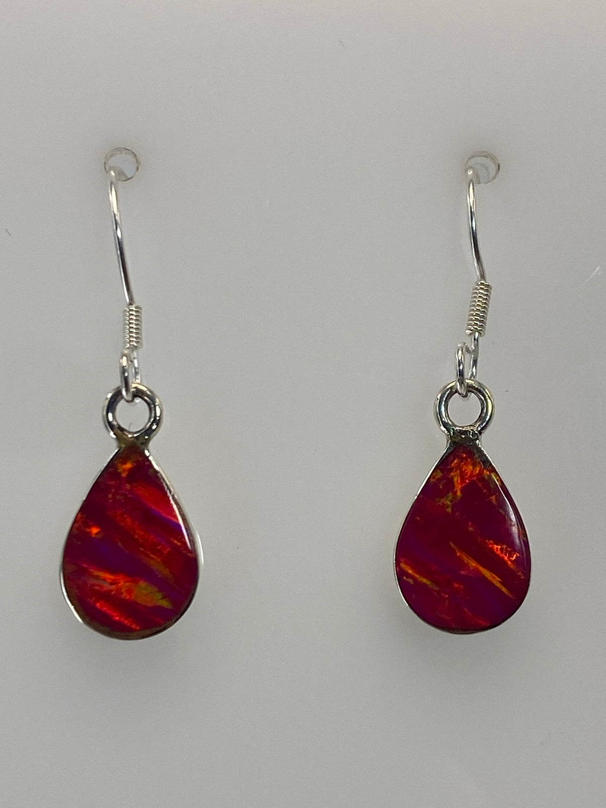 Par de aretes de plata con ópalo de fuego rosa sobre fondo blanco