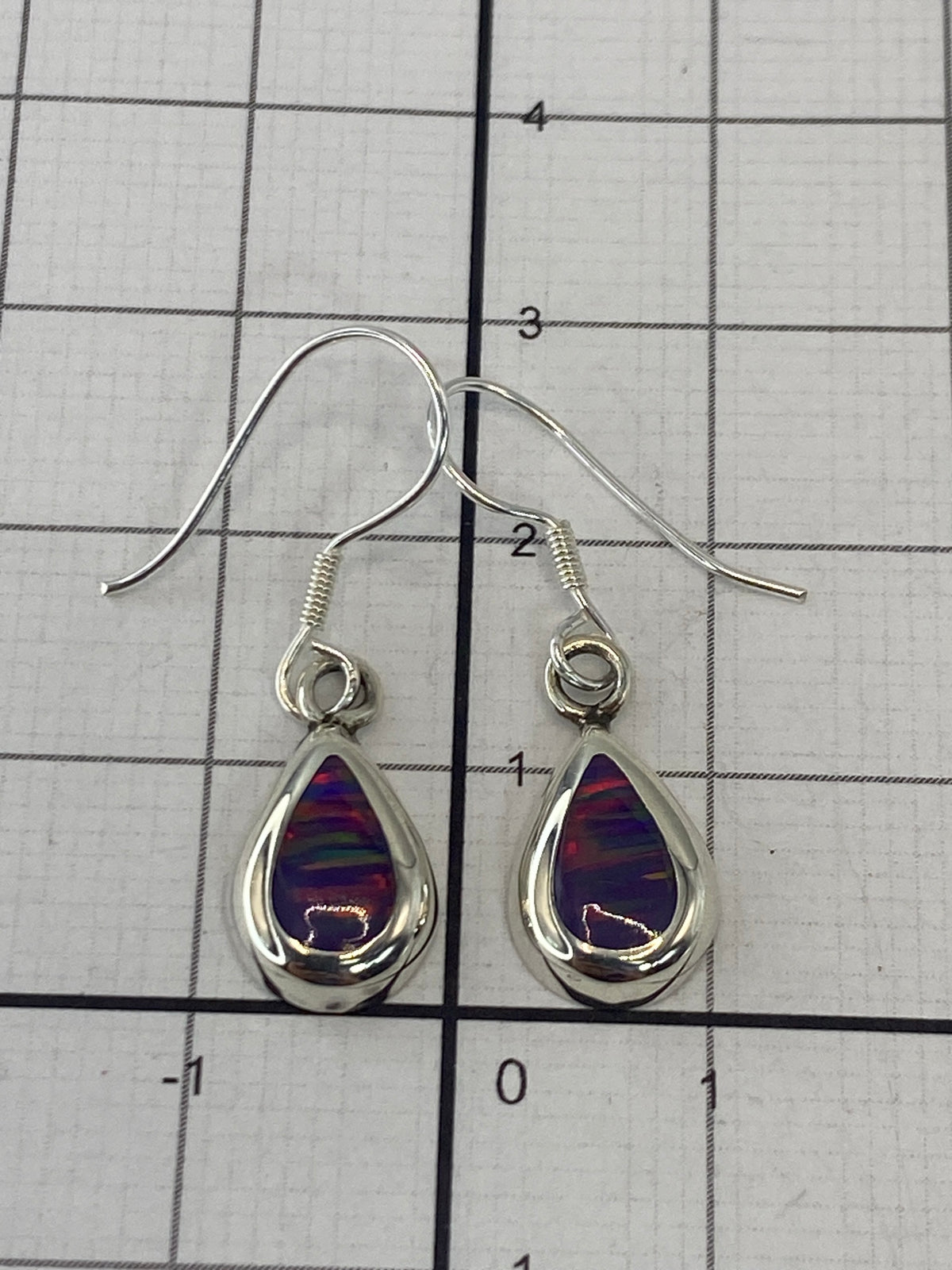 Aretes de plata con ópalo morado en la mano, reflejos del fuego interno de la piedra