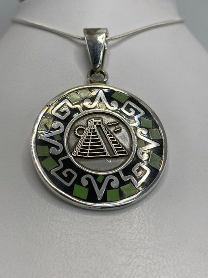 Detalle frontal del dije mostrando la pirámide de Chichén Itzá y motivos prehispánicos grabados