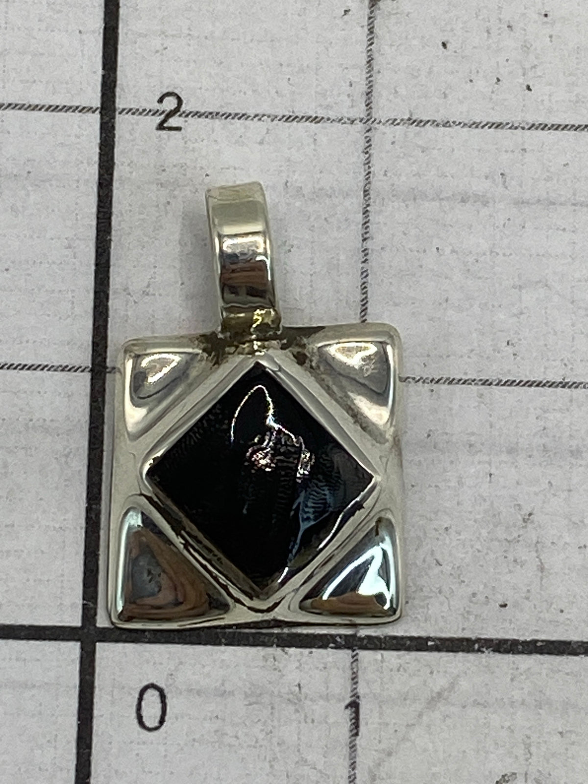 Dije de 1.8 cm de largo sobre escala de medición para referencia de tamaño