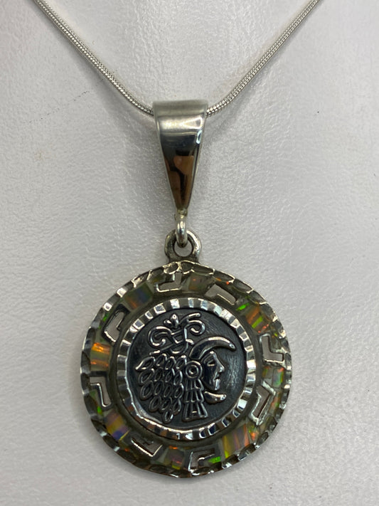 Dije de plata 950 con motivo prehispánico y ópalo multicolor engastado, colgando de cadena plateada