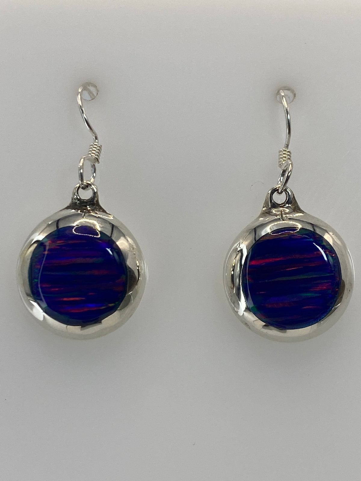 Par de aretes de plata con ópalo de fuego azul profundo, vistos de frente