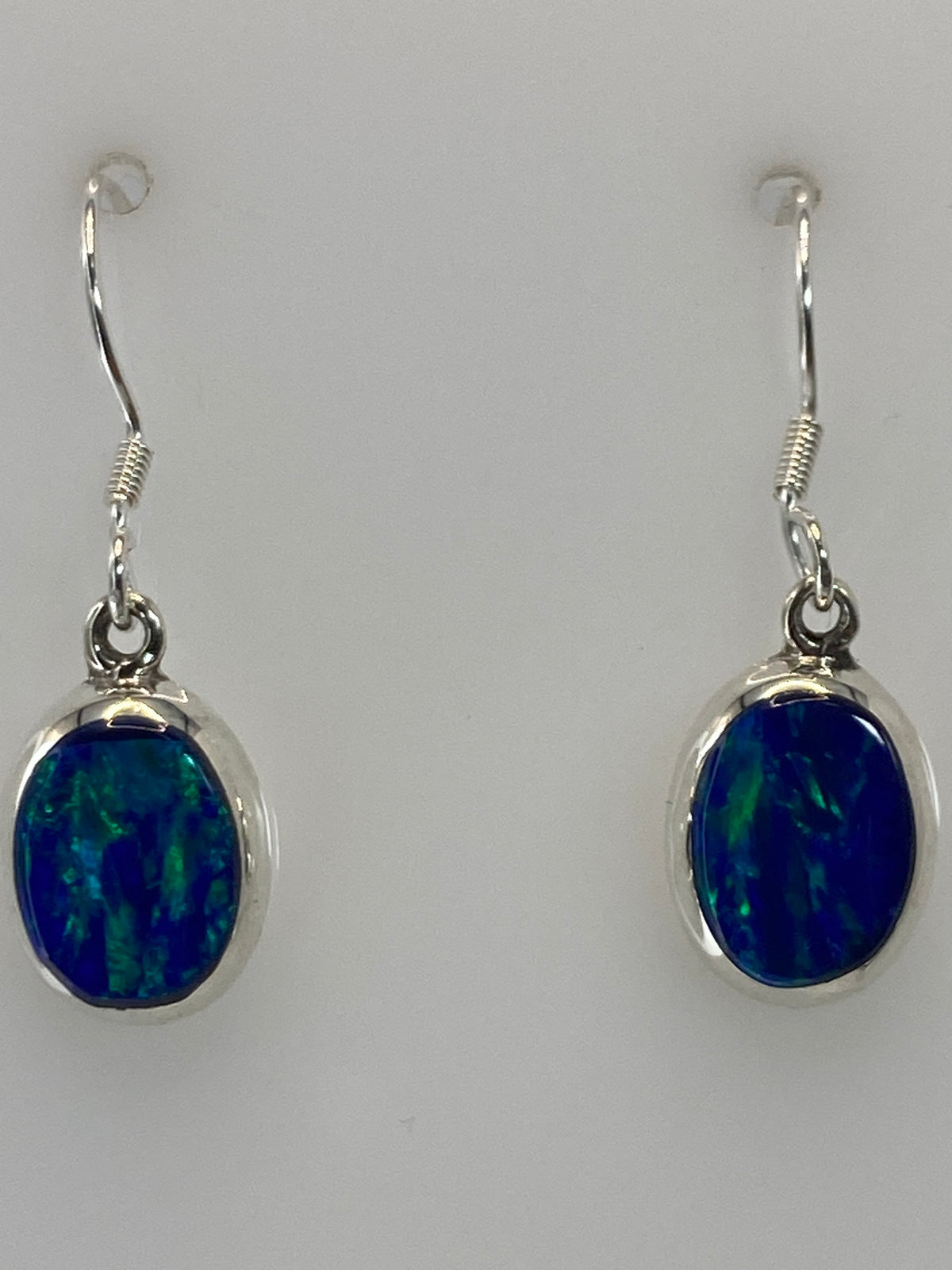 Los aretes de frente mostrando el brillo del ópalo y los ganchos de plata