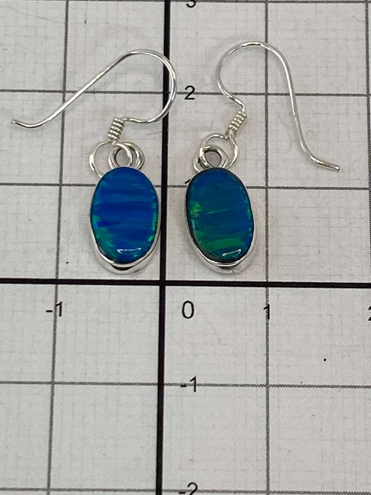 Aretes de plata con Ópal de Fuego mostrando el brillo de la piedra azul