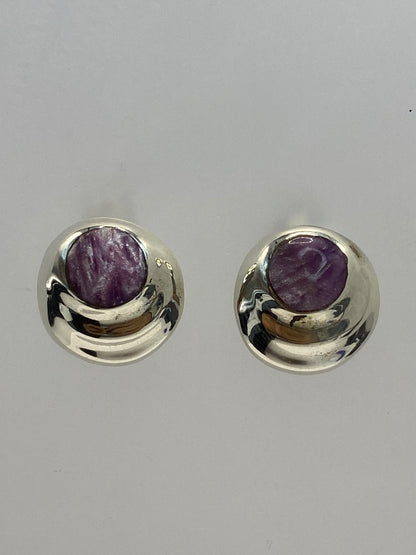 Par de aretes de plata 925 con piedra morada engastada, colgando sobre fondo blanco