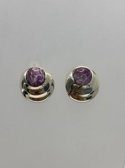 Detalle frontal de los aretes mostrando la incrustación de la piedra morada en la plata