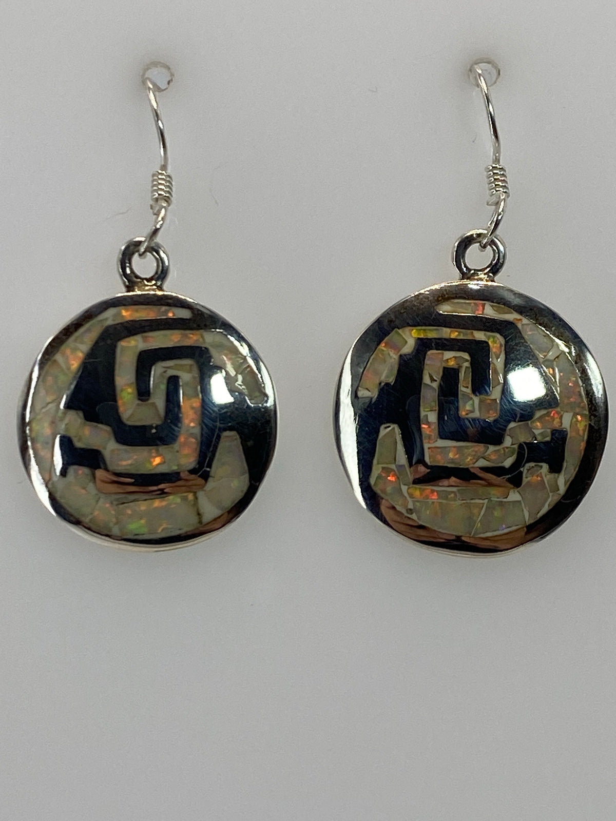Aretes de plata 950 con ópalo de fuego multicolor colgando sobre fondo blanco