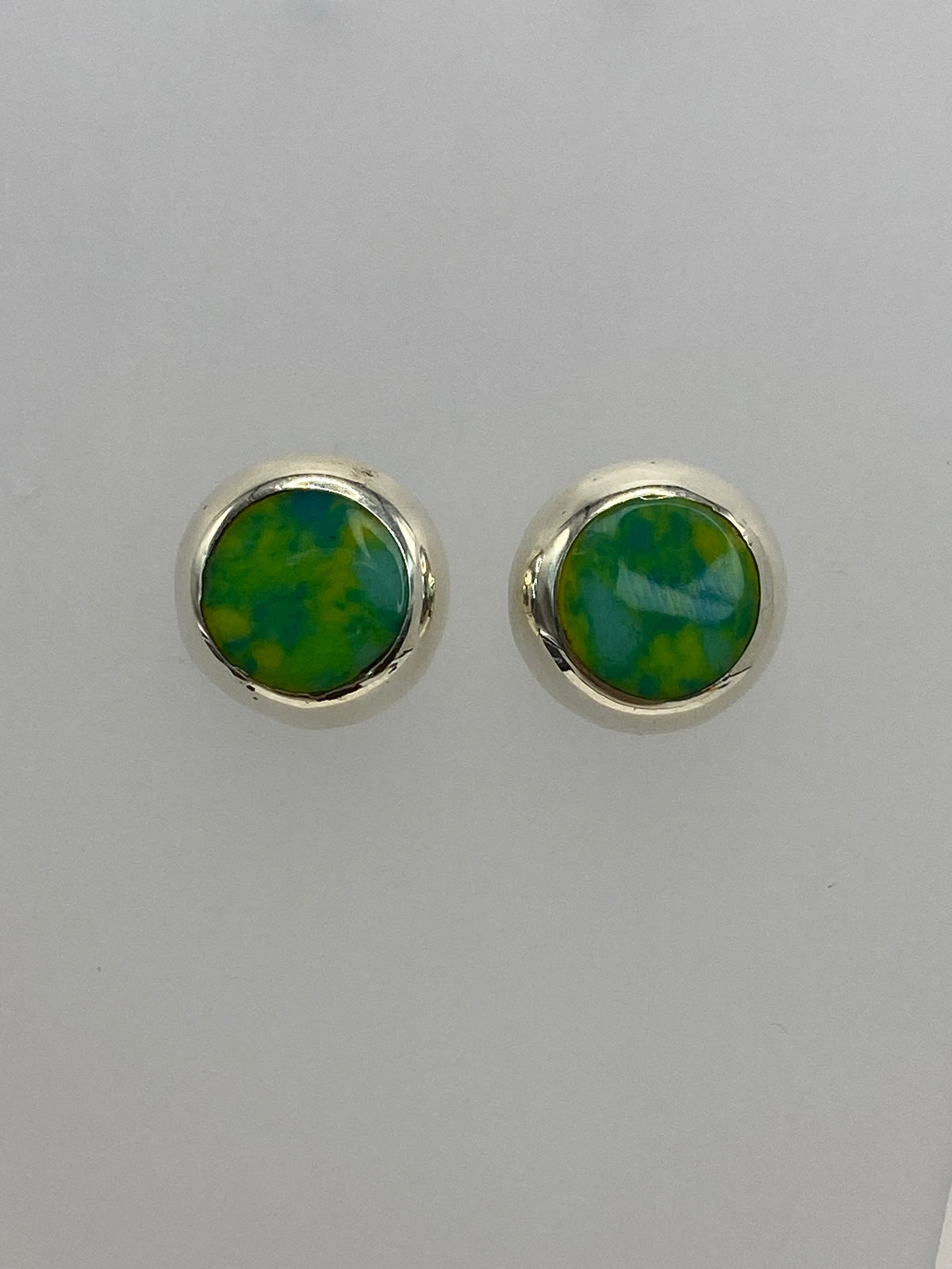Arete individual de plata con piedra multicolor mostrando incrustación detallada