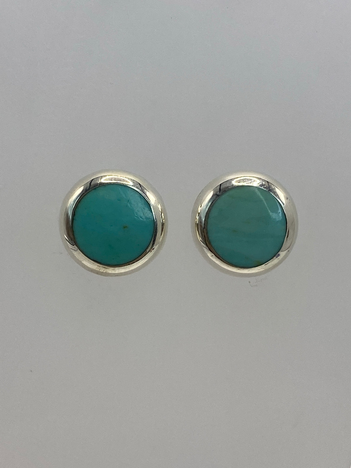 Par de aretes de plata 925 con piedra azul cielo engastada, sobre fondo blanco