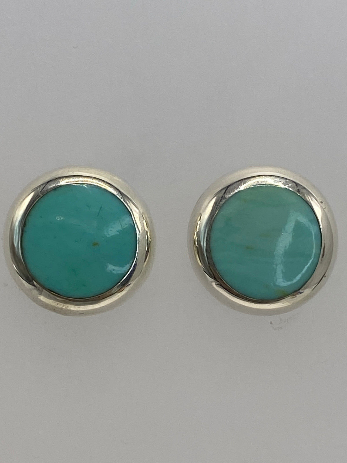 Aretes de plata pequeños con piedra azul cielo vistos desde ángulo frontal