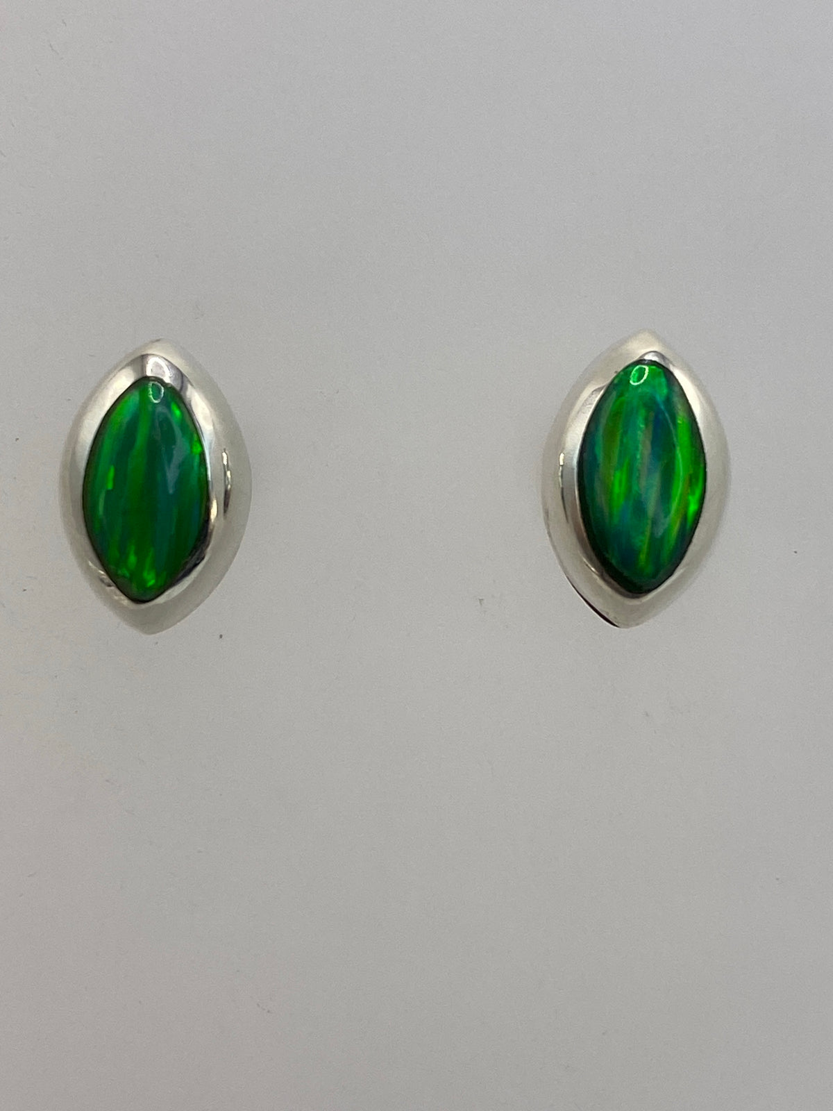Aretes con ópalo de fuego sobre regla de centímetros mostrando tamaño real de 1.4 cm
