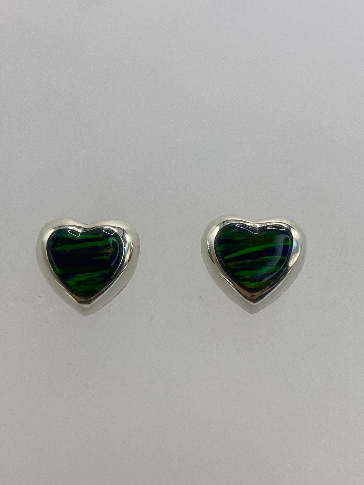 Par de aretes de plata 925 con ópalo de fuego verde engastado, vistos de frente sobre fondo blanco