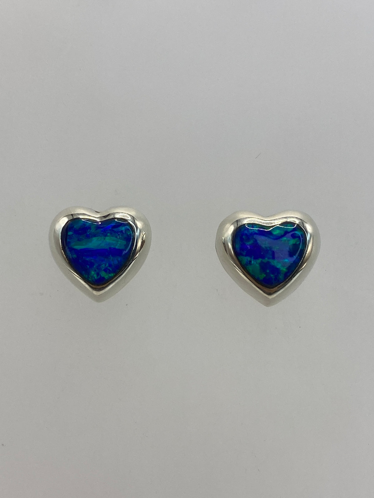 Par de aretes de plata con ópalo de fuego azul sobre fondo blanco