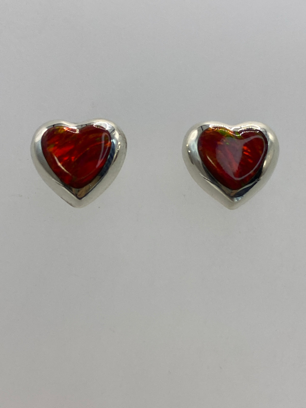 Detalle frontal de los aretes mostrando el tono rojo intenso del Ópalo de Fuego