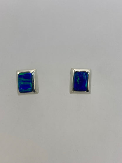 Par de aretes de plata con ópalo de fuego azul cielo engastado, sobre fondo blanco