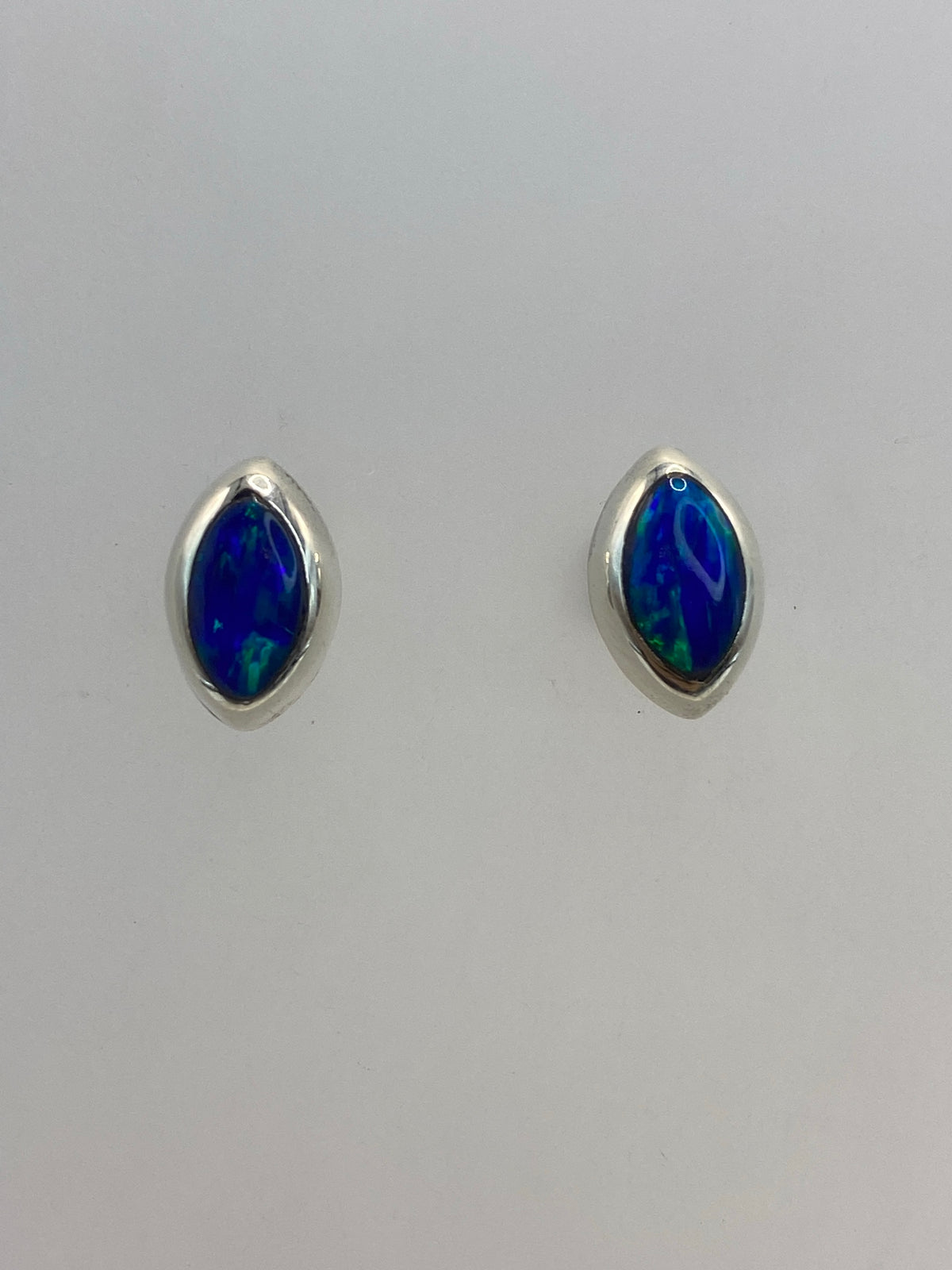 Par de aretes de plata con ópalo de fuego azul sobre fondo blanco