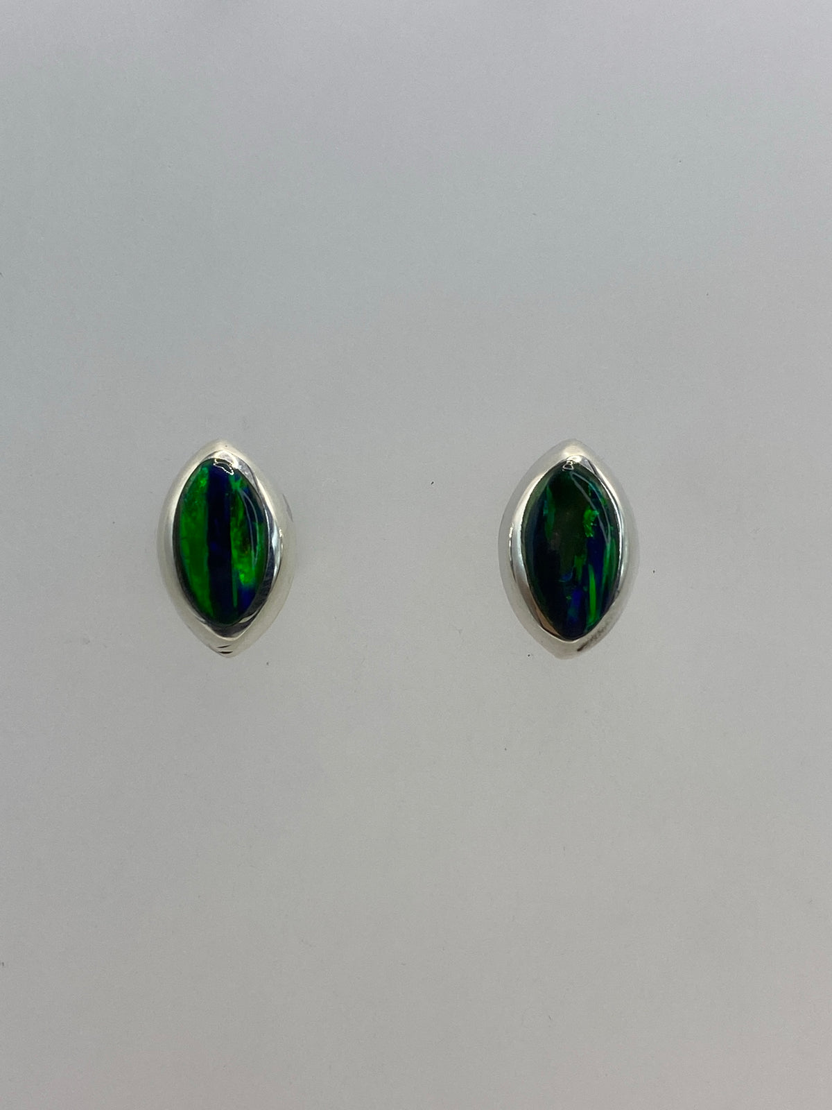 Par de aretes de plata con ópalo de fuego verde engastado, vistos de frente