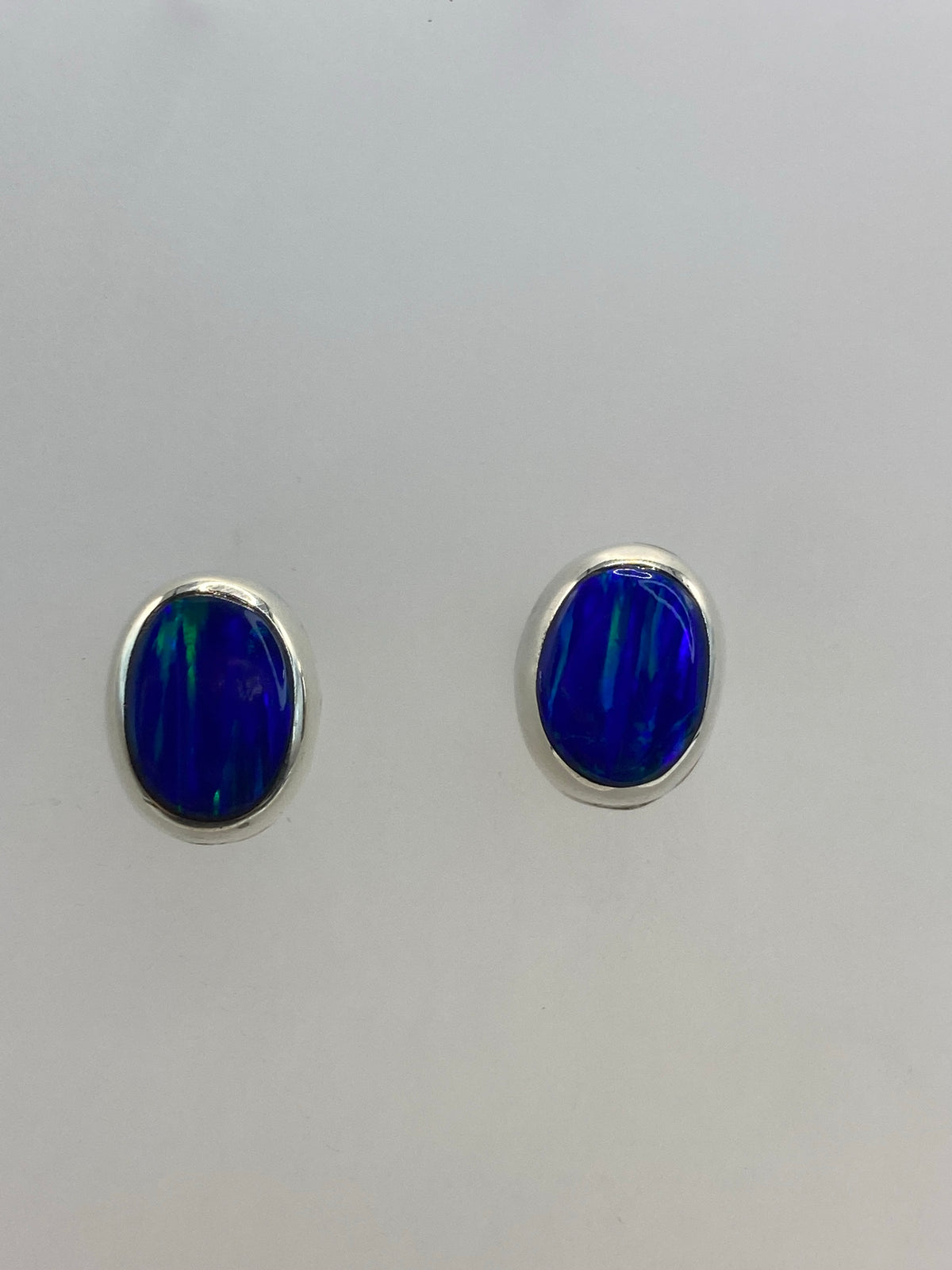Aretes de plata con ópalo de fuego azul, par completo sobre fondo blanco