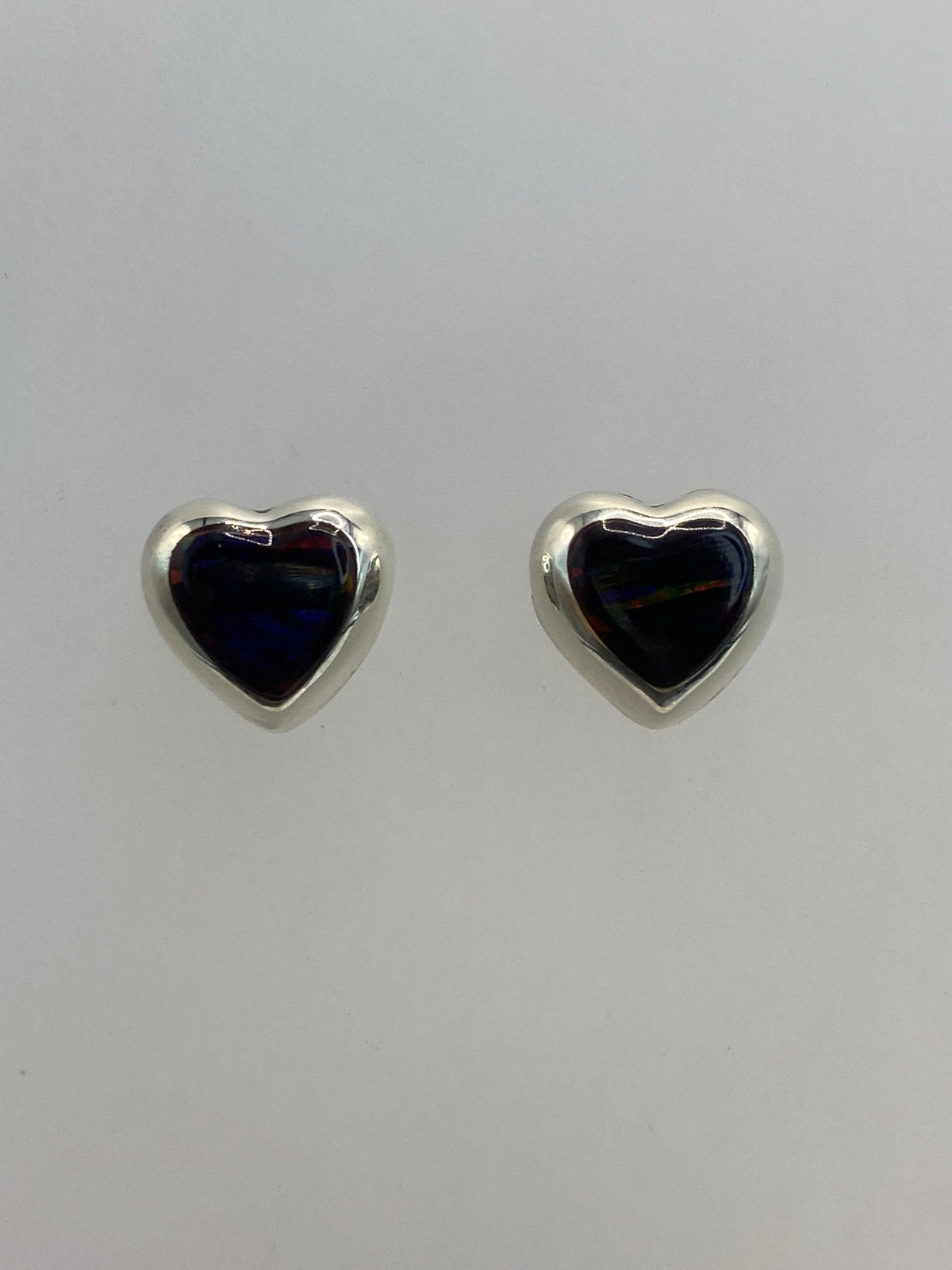 Par de aretes corazón de plata con ópalo de Fuego anaranjado y rojo sobre fondo gris