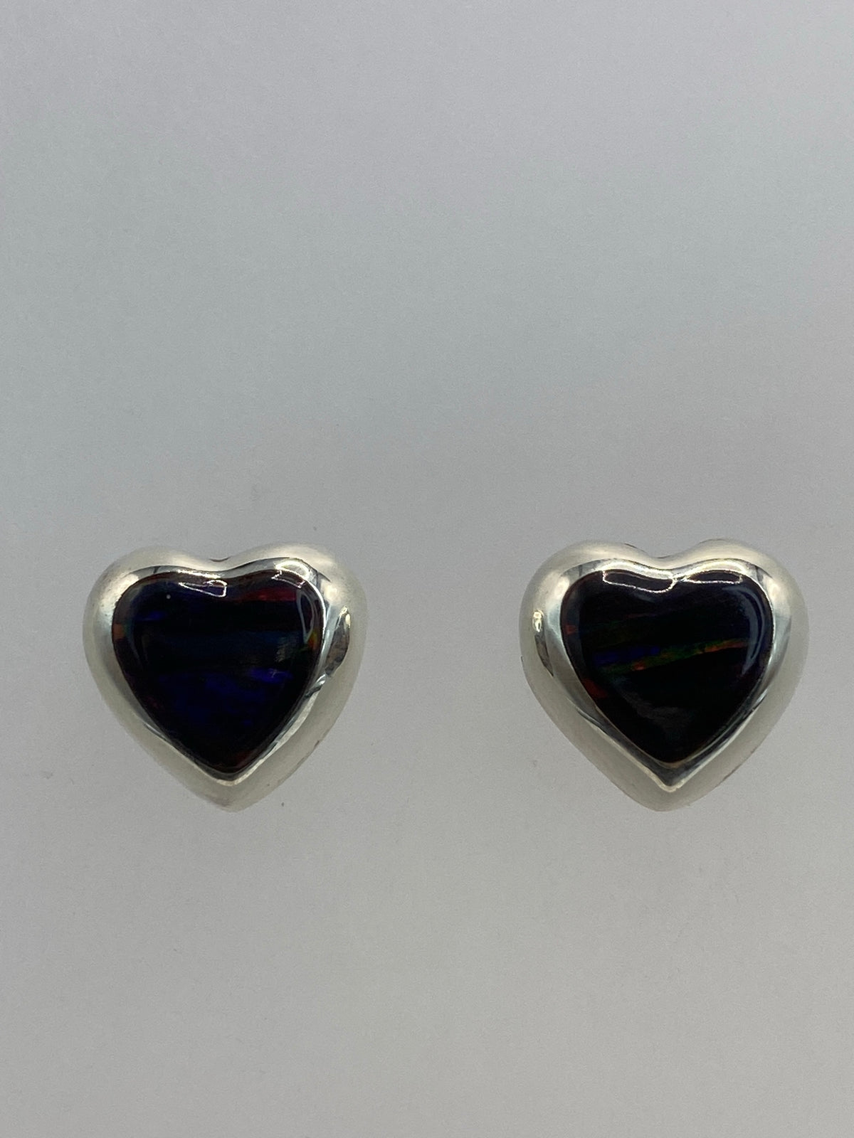 Vista lateral del par de aretes en corazón, con cierre de estuche
