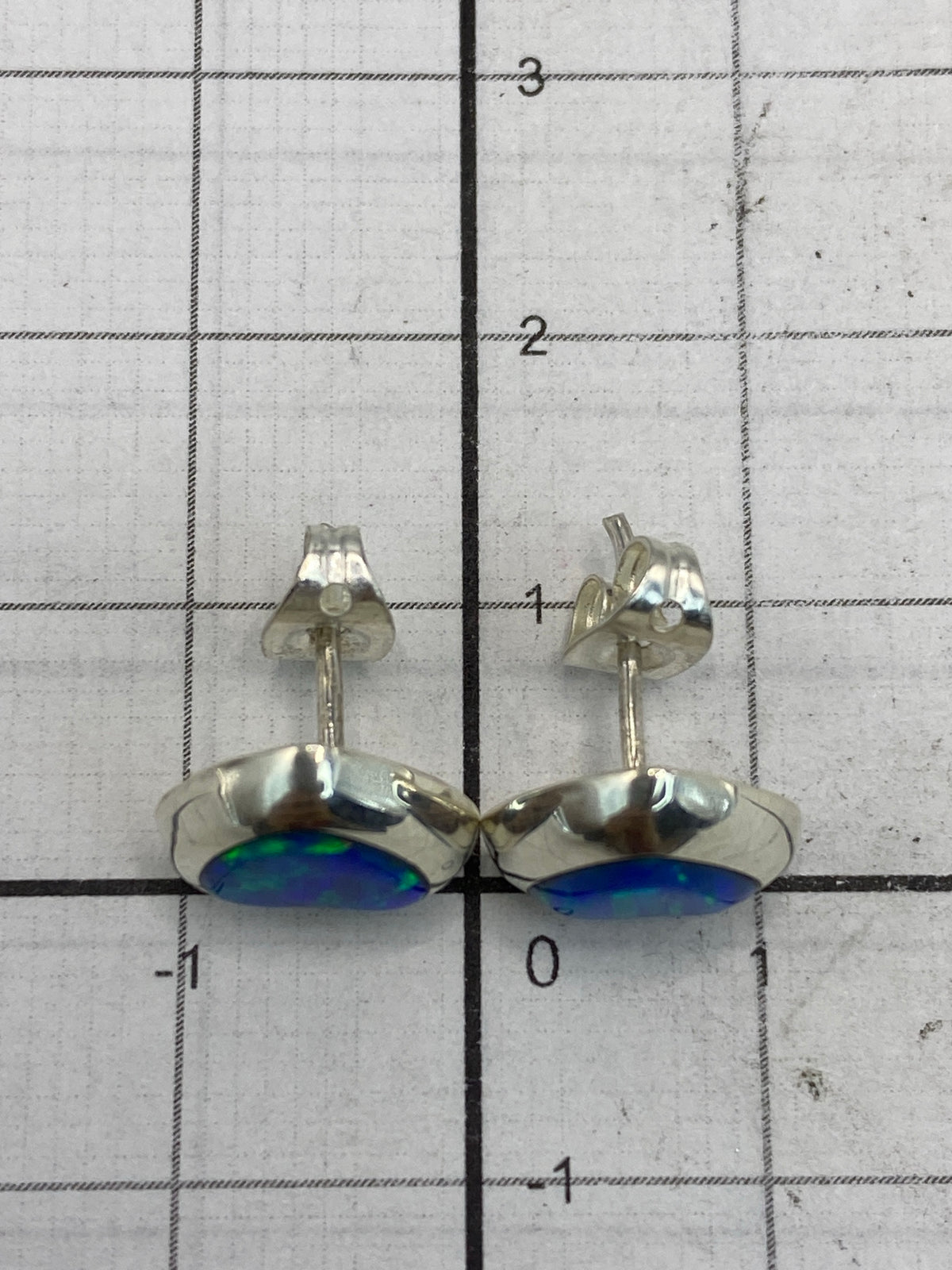 Aretes sobre escala mostrando el peso total de 1.3 g y sello 925