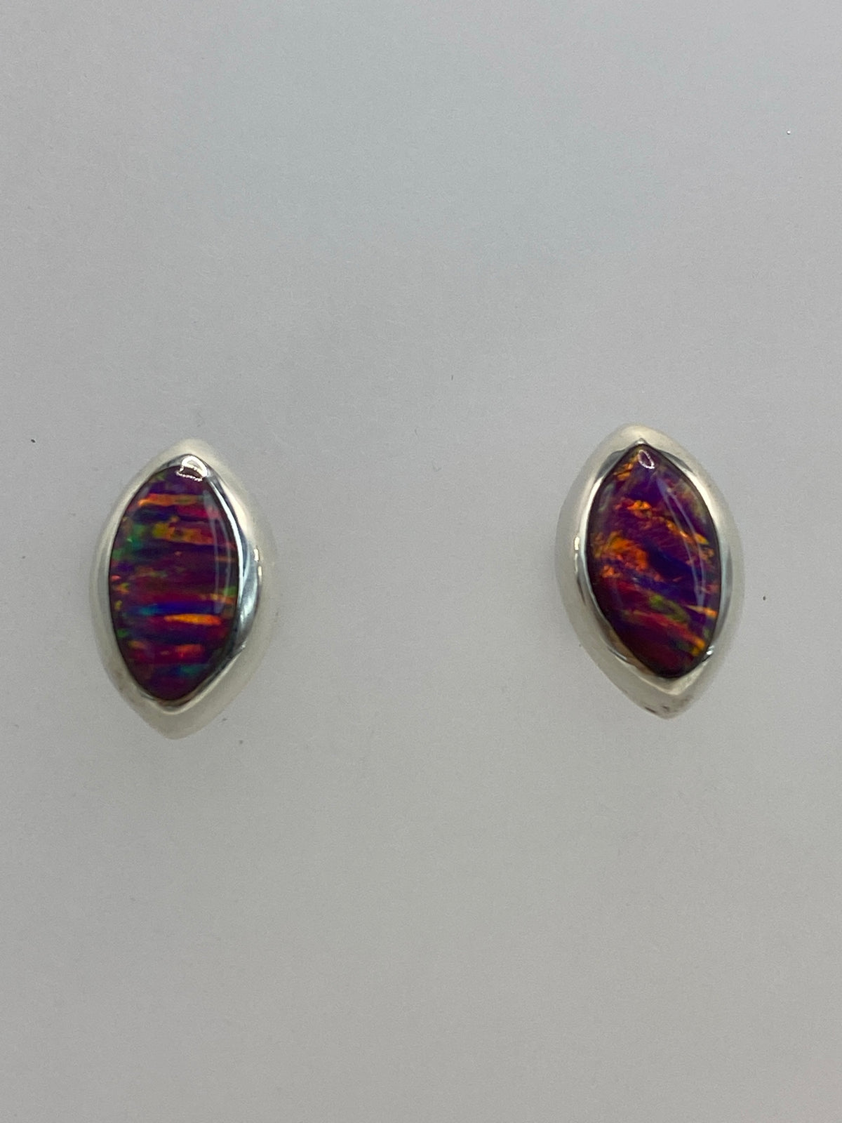 Aretes de ópalo morado sobre fondo blanco mostrando el Quinto 950