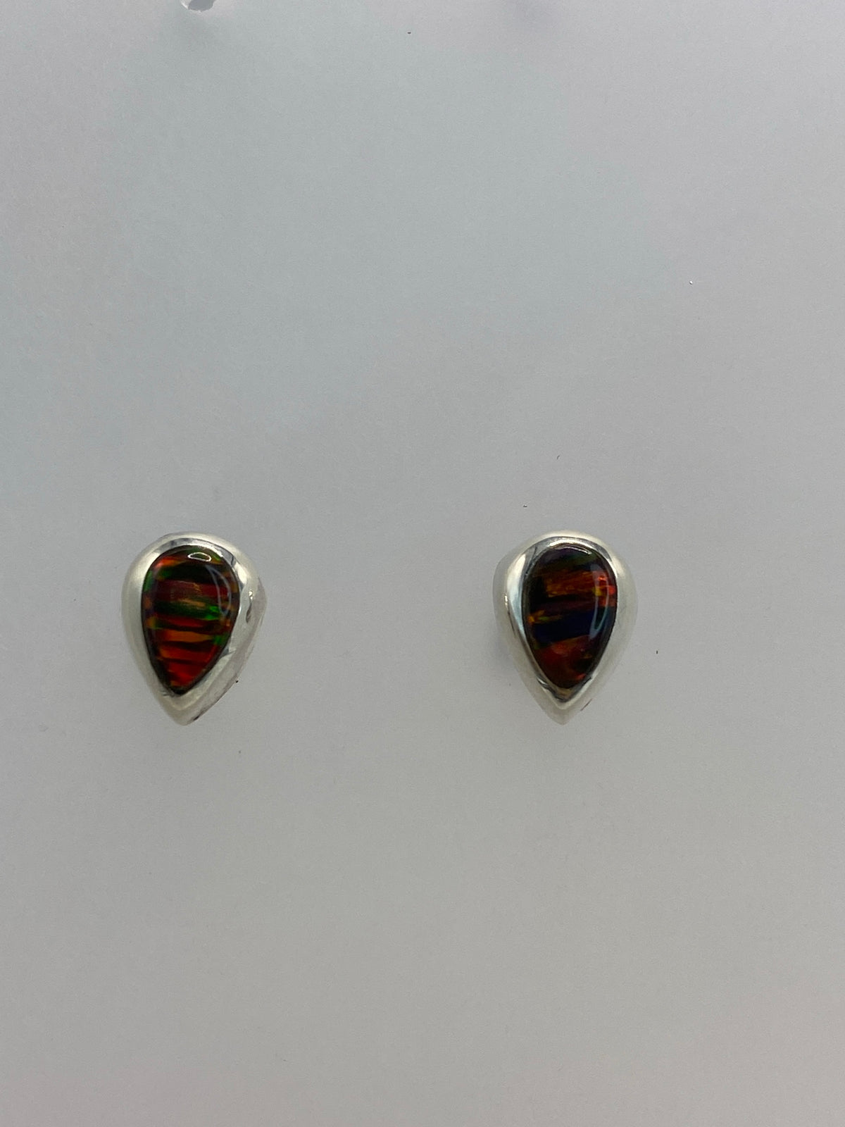 Par de aretes de plata con ópalo de fuego multicolor, vistos de frente en estudio