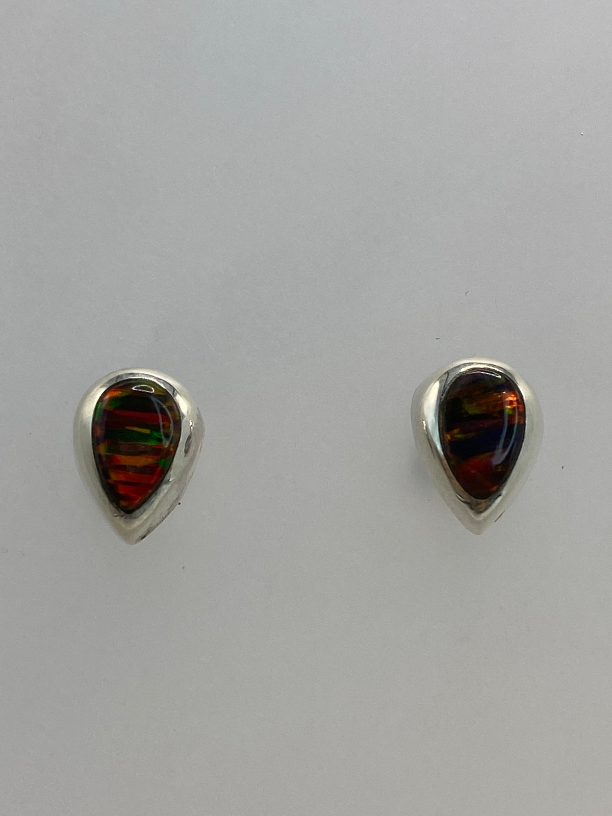 Aretes puestos en lóbulo mostrando el brillo multicolor del ópalo