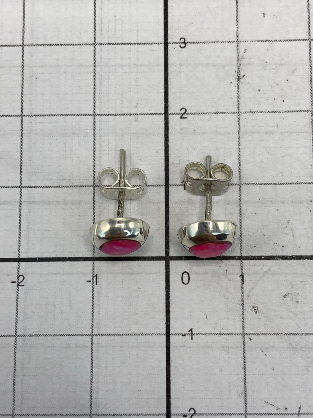 Aretes en la balanza de joyería mostrando 1.0 gramo de peso total