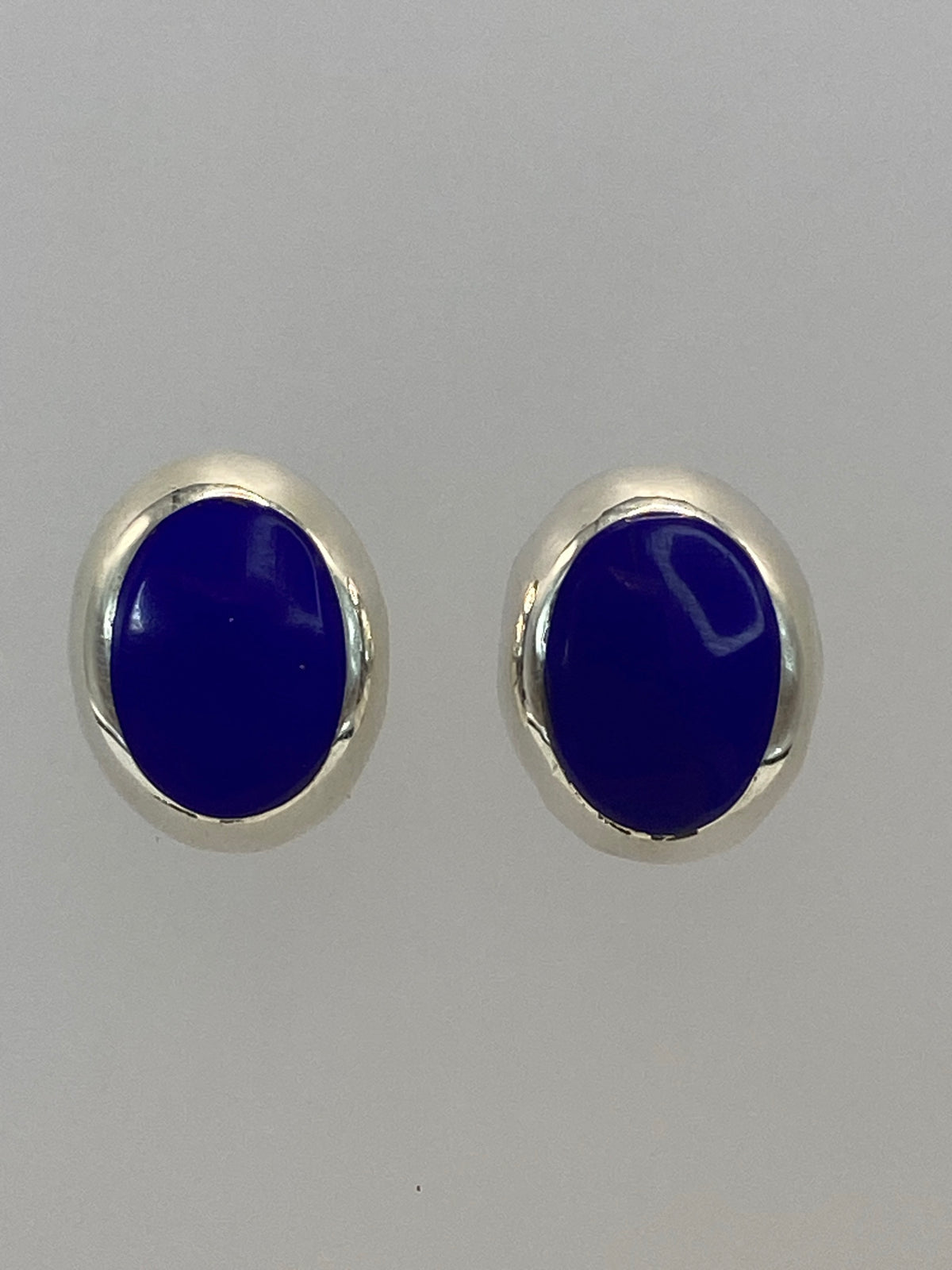 Par de aretes de plata con piedra azul oval engastada, vista frontal