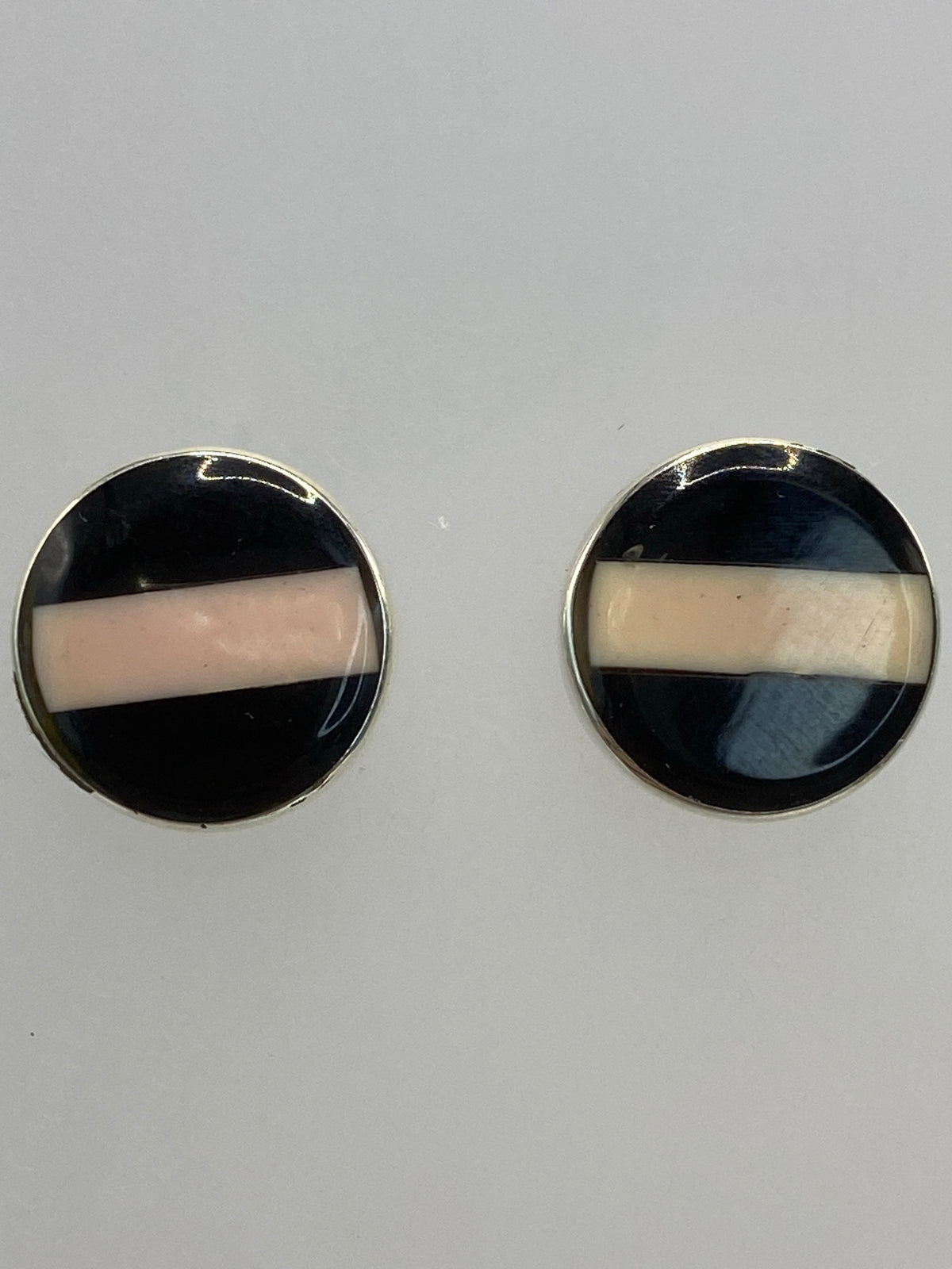 Aretes de plata con piedra multicolor en la oreja, mostrando el tamaño y brillo
