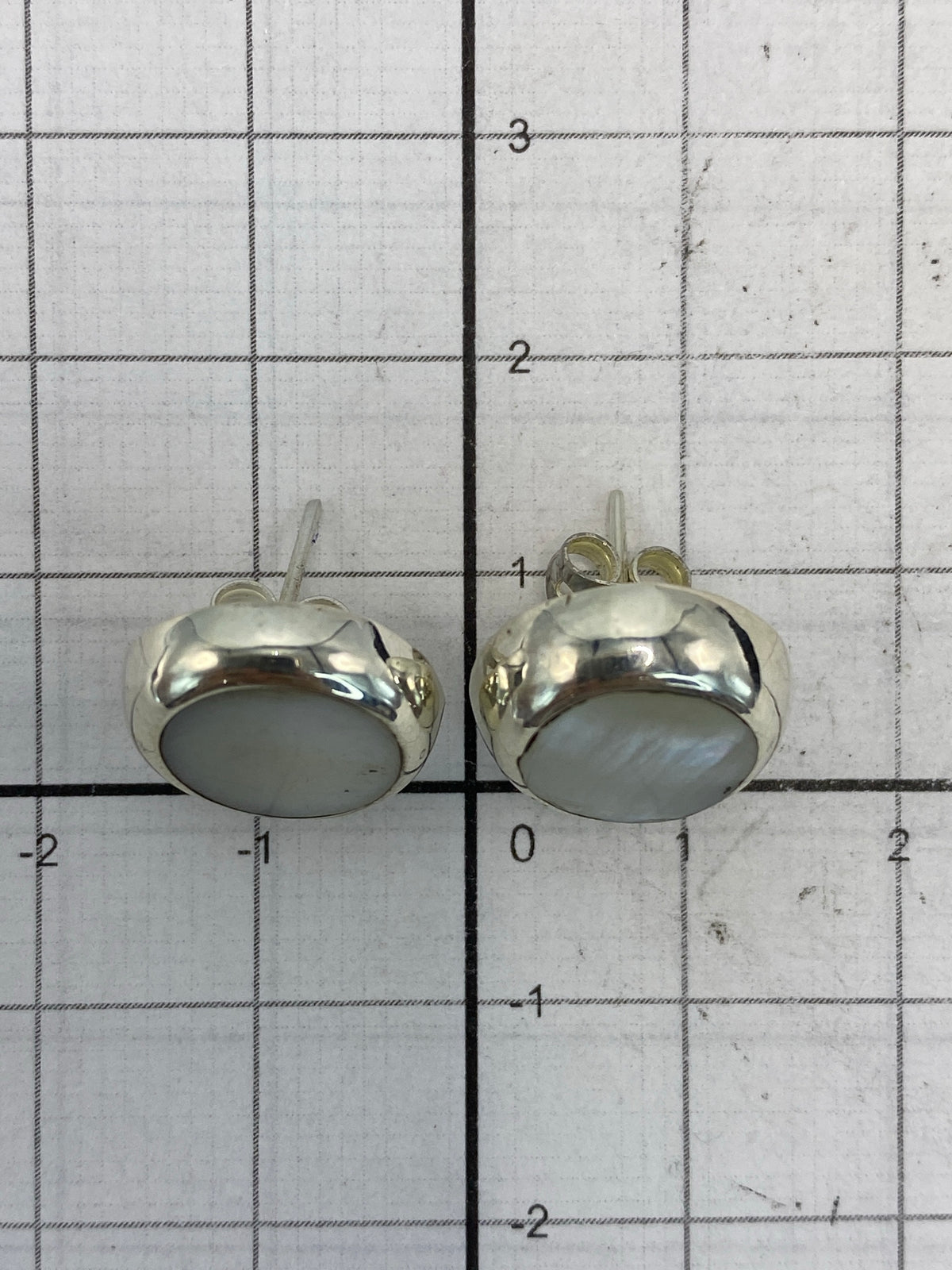 Par de aretes de plata colocados en balanza con peso de 2.6 gramos